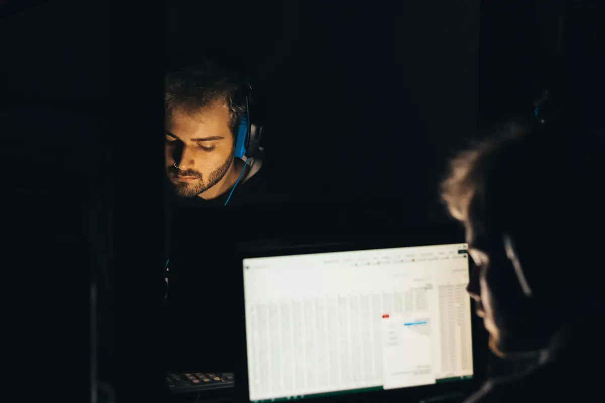 A developer with headphones, lit by his monitor